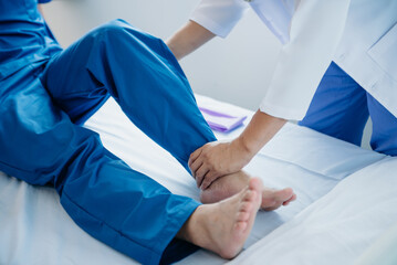 Physiotherapist Helping Patient While Stretching His Leg in bed in clinic .
