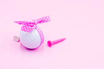 Golf ball with pink ribbon on pink background