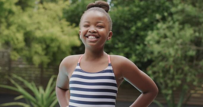 Portrait of happy african american girl wearing swimsuit in garden in slow motion