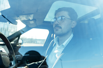 Fototapeta na wymiar Young businessman in elegant suit driving luxury car