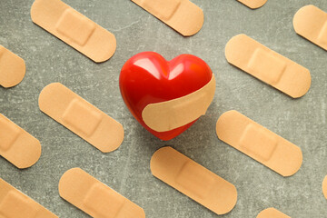 Red heart and adhesive plaster on gray textured background