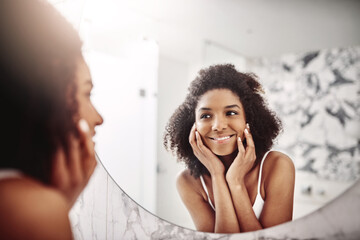 Woman, skincare and dermatology in mirror with a smile in the bathroom for wellness at a hotel....