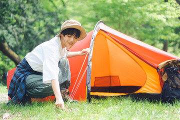 ソロキャンプをしている若い日本人女性/テントをたてる