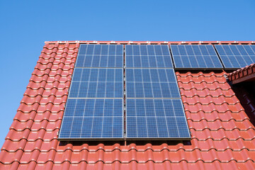 solar panels on a red tiled roof, blue sky, no clouds, sunny day