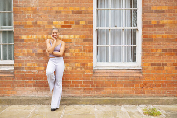 Portrait of hipster young woman standing in front of brick wall