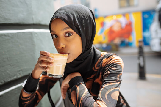 Portrait of young woman in hijab drinking coffee