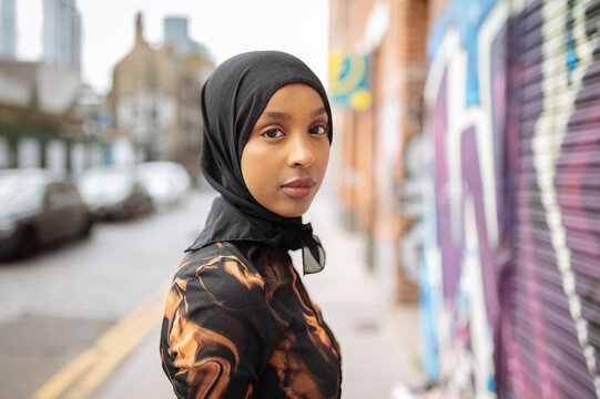 Portrait of young woman in hijab walking in street