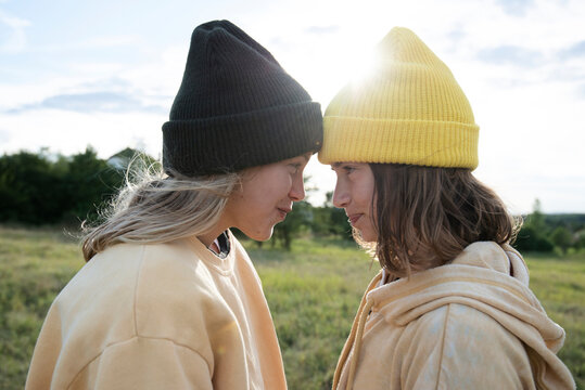 Smiling girl friends wearing beanies in field