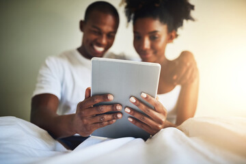 Tablet, bedroom and happy couple in home with movie, video or communication on social media app. Black man, woman and digital touchscreen in house with reading, online chat or smile at meme together