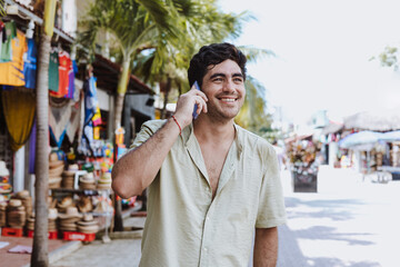 hispanic young man talking by mobile phone on vacations or holidays in Mexico Latin America,...
