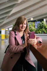 Fototapeta premium Senior woman using smartphone at airport