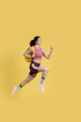 Fototapeta na wymiar Female jogger with yellow backpack, jogging marathon, fast running, speed race on yellow background
