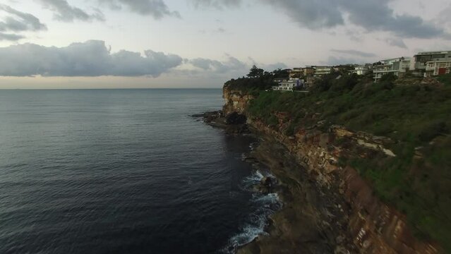 Fly along cliffs by the ocean, early morning light.