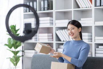 Asian business woman on sofa using a laptop computer checking customer order online shipping boxes at home. Starting SME Small business entrepreneur freelance. Online business, SME Work home concept.