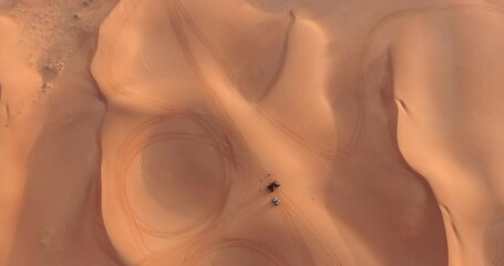 The drone flies over a group of ATVs standing on the desert sand