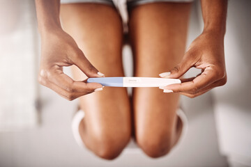 Hands, healthcare and closeup of a woman with a pregnancy test in the bathroom of her home. Maternity, motherhood and zoom of female person with pregnant stick device for announcement in modern house