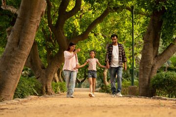 Fototapeta premium couple walking in the park with daughter