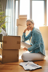 Woman, boxes and portrait with document on the floor with a smile at a new home for investment. Property, box and paperwork with happiness for investing in real estate for finance and retirement.