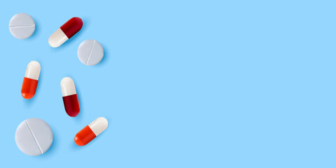 White pills and red-and-white pills on a blue background. The concept of treatment and recovery. A health design element for apps, websites and social networks. Medicinal pills.