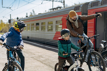 man and children on bicycles on train station travelling to countryside
