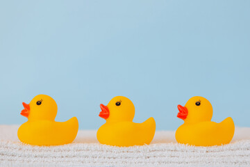 Stacked white towels and bath ducks on blue background
