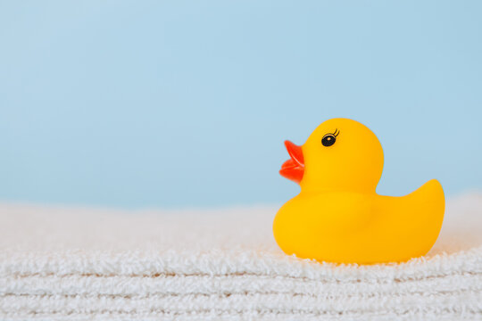 Stacked white towels and bath duck on blue background