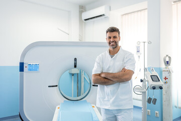 Confident male doctor oncology in magnetic resonance imaging or computed tomography room of a...