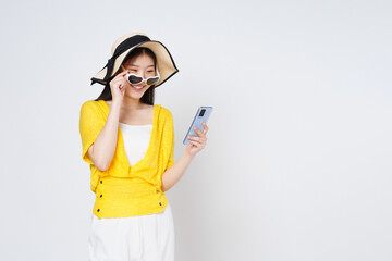 Young woman using smart phone and smiling wearing a sun hat and sunglasses isolated on white background.