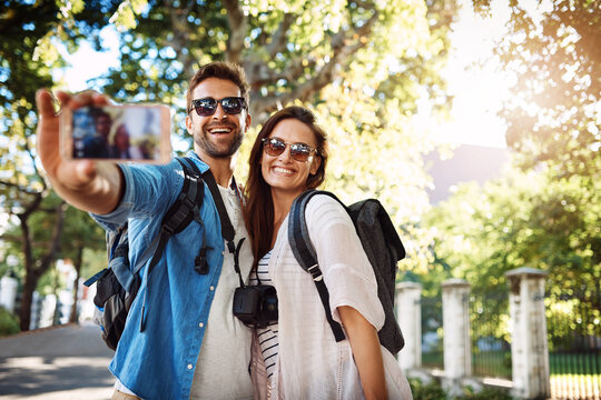 Selfie, happy couple and outdoor for travel with a smile for holiday memory and happiness. Man and woman at a park with trees for adventure, journey or vacation photo and freedom with love and care