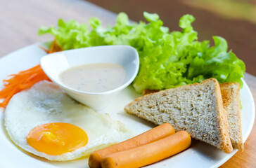 Breakfast consisting of fried eggs, smoked sausages Bread and Caesar Salad
