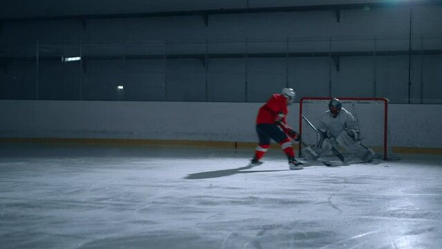Ice hockey player in red jersey showing off his incredible agility and speed on the dark ice arena