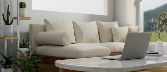 Close-up image of a laptop on a coffee table in cozy contemporary living room.