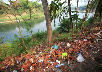 Rubbish, plastic bottles cans, paper by the Nam Khan / Mekong river in Luang Prabang.