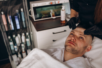 Cosmetologist applying mask on client's face in spa salon, above view