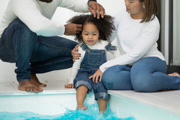 Happy multiracial family having fun at home together. Portrait of multiethnic father mother and little biracial daughter sitting at swimming pool relaxing. Diverse ethnic dad and mom playing with kid.