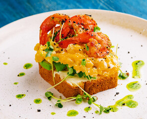 Scrambled eggs with avocado and shrimps on plate
