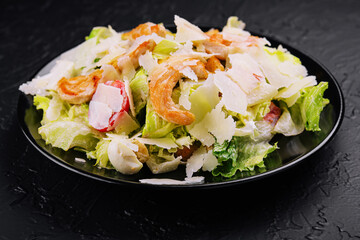 Delicious fresh caesar salad on black plate