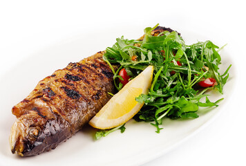 Grilled sea bream fish, lemon, arugula on white plate