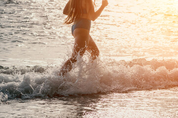 Running woman on a summer beach. A woman jogging on the beach at sunrise, with the soft light of the morning sun illuminating the sand and sea, evoking a sense of renewal, energy and health.