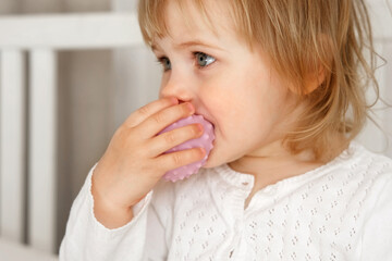 Cute baby girl playing tactile wooden and silicone toys. Young child hand plays sensory massage ball. Enhance the cognitive, physical process. Brain development. Teething toy. Dentition. Baby's teeth