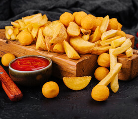 Assorted beer snacks like potato wedges, french fries and cheese balls