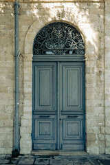 Fototapeta na wymiar Old-fashioned gray wooden front door with transom window in natural stone doorway 