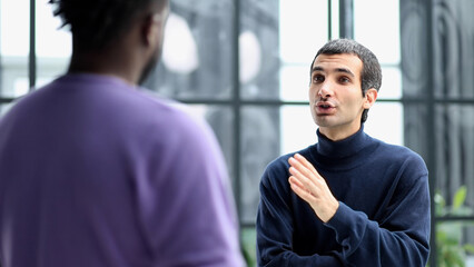 Diverse friendly male colleagues talking while walking