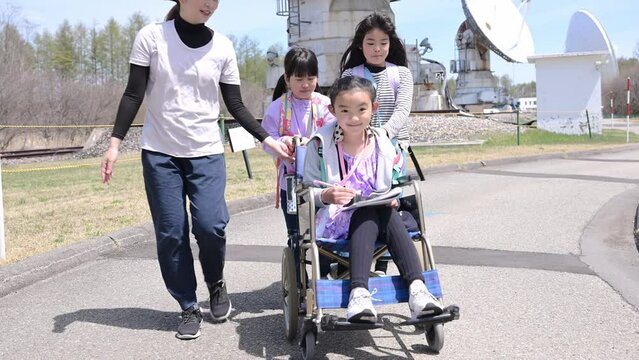 車いすに乗った女の子と学校の遠足に行く小学生の友達