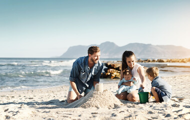 Fototapeta premium Sandcastle, happy summer and children at the beach with bonding, love and support. Baby, mom and dad together with kids playing in the sun with mockup space and smile by the ocean and sea with family