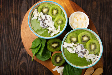 Green Smoothie Bowl with Spinach, Banana, Chia Seeds on Brown Background