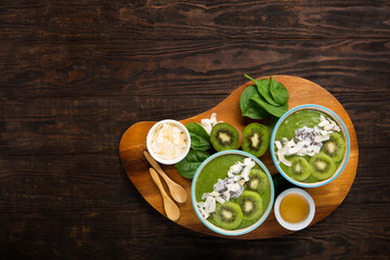 Green Smoothie Bowl with Spinach, Banana, Chia Seeds on Brown Background