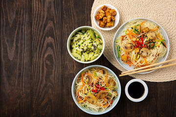 Vegan Rice Noodles with Tofu, Peppers, Carrots on Dark Brown Background