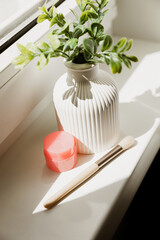 Handmade gypsum vase by the window with flowers. Lip balm with makeup brush for store content. Mini vase for dried flowers and natural flowers.