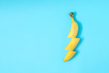 Banana in the form of light bolt on a blue background. Creative food concept.